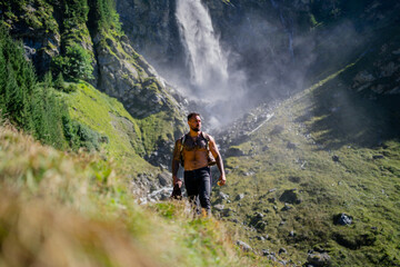 Man hiker on summer vacation. Tourist hiker with muscular torso. Strong Hispanic Tourist Hiker outside. Hiker walking near the waterfall. Traveling on nature. Carefree hiking. Hiking on mountain.