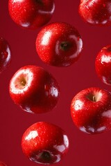 Bright red apples float mid-air against a deep red backdrop, showcasing their vivid color and glossy texture