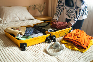 Woman packing suitcase on bed for a new journey packing list for travel planning preparing...