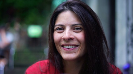 Portrait of a woman in her late 30s smiling warmly at the camera outdoors. a genuine and friendly expression, highlighting natural beauty and a moment of candid joy
