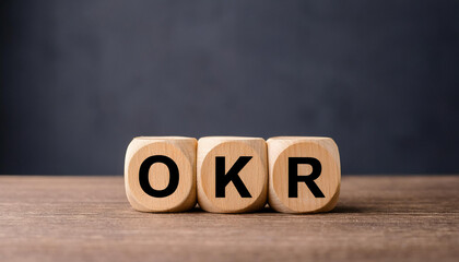 Wood cubes with abbreviation text OKR on wooden table. Objectives and Key Results.