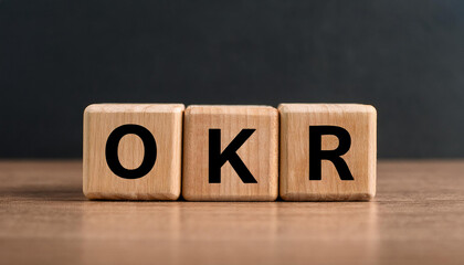 Wood cubes with abbreviation text OKR on wooden table. Objectives and Key Results.