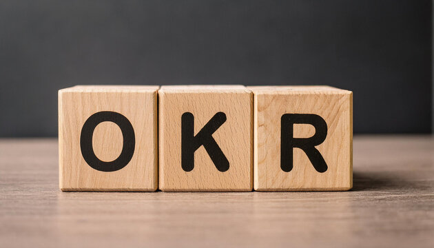 Wood cubes with abbreviation text OKR on wooden table. Objectives and Key Results.