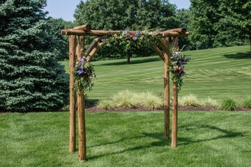 Fototapeta premium Rustic Wooden Archway Decorated with Colorful Flowers in a Grassy Outdoor Setting