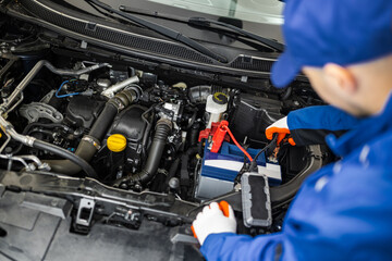 A mechanic is working on a car's battery in a garage