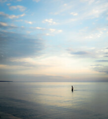 Calm sea at sunrise with lone person in water