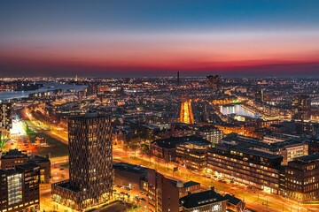 A stunning cityscape showcases modern skyscrapers along a river, illuminated by the warm glow of...