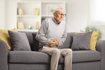 Elderly man with abdominal pain sitting on sofa