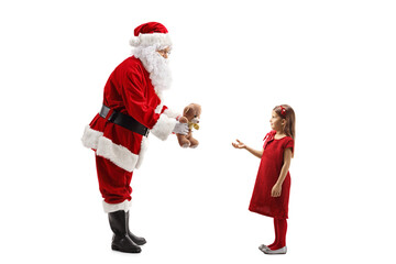 Full length profile shot of Santa Claus giving a teddy bear to a girl