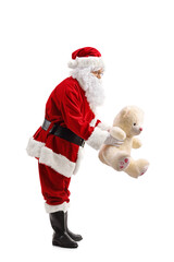Full length profile shot of Santa Claus holding a teddy bear