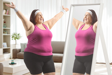 Cheerful overweight woman in sportswear looking at a mirror