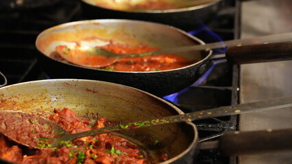 Three frying pans bubble away on a gas stove, the first pot bubbles with a rich tomato sauce, flecked with herbs. The second, a creamy concoction, glimmers as it simmers. The last, is a spicy mix.