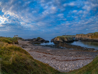 Fototapeta premium Atardecer en Valdoviño. Paisaje en el que se puede ver a la izquierda la pequeña Ermita do Porto y a la derecha el faro de Punta Foruxeira 
