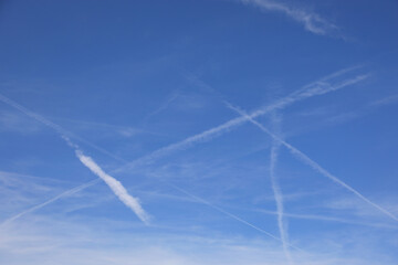 white contrails stretch across a bright blue sky creating a sharp contrast while evoking thoughts...