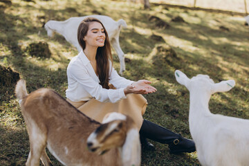 Woman Enjoying a Peaceful Day in Nature With Friendly Goats in a Sunny Pasture Setting
