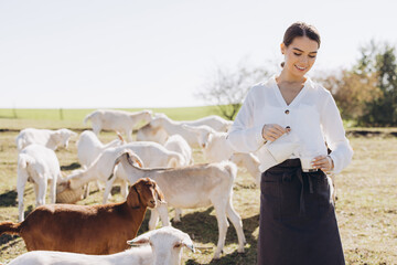 Young Woman Enjoys a Peaceful Day on the Farm While Pouring Fresh Goat Milk Outdoors in a Scenic...