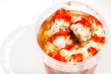 Container with Surimi in the form of shrimp on a white background.