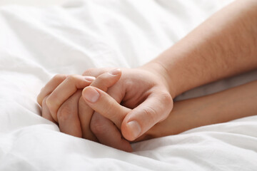 Lovely couple holding hands in bed, closeup