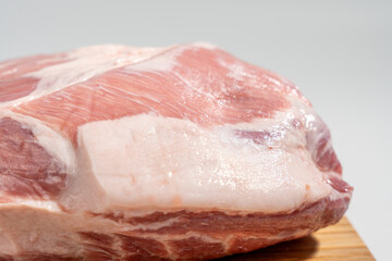 A piece of meat with a lot of fat on a wooden cutting board.