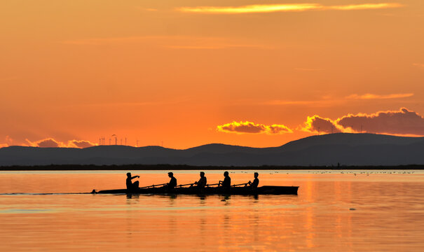 Silhouette of persons rowing on a boat at sunset	