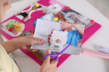 Creating vision board. Girl cutting out picture at light table, closeup