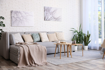 Light living room interior. Comfortable sofa near white brick wall indoors