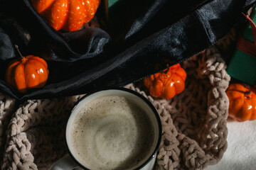A white ceramic mug with cappuccino stands against the background of boxes with gifts and pumpkins. Preparation of gifts, packaging. Table Decoration