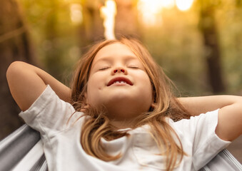 Carefree happy little girl outdoors relaxing in the sunshine 