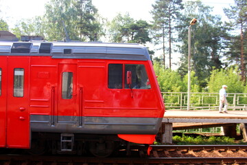 The electric train stands at the station in summer.	