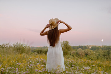 Woman in Sunflower Field: Happy girl in a straw hat posing in a vast field of sunflowers at sunset, enjoy taking picture outdoors for memories. Summer time.