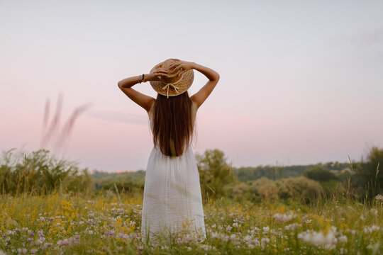 Woman in Sunflower Field: Happy girl in a straw hat posing in a vast field of sunflowers at sunset, enjoy taking picture outdoors for memories. Summer time.