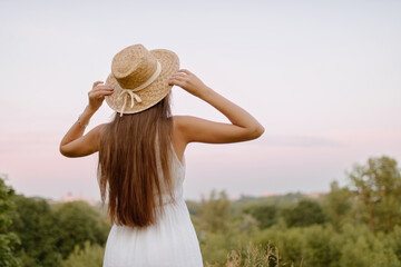 Woman in Sunflower Field: Happy girl in a straw hat posing in a vast field of sunflowers at sunset, enjoy taking picture outdoors for memories. Summer time.