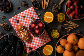 Top view of Guagua de pan with cup of colada morada, traditional Ecuadorian food for the day of the dead, surrounded by the ingredients to cook the colada