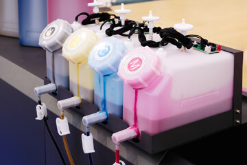 row  ink tanks with different colors. tanks are connected to machine that dispenses the ink....