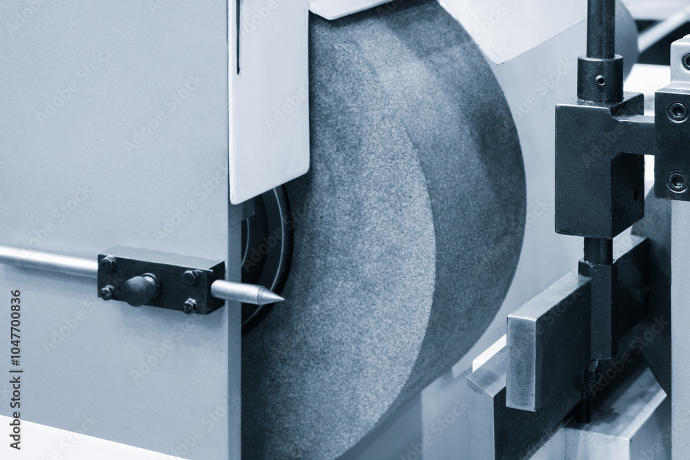 Poster a machine with a grinding wheel and a sharp point. the grinding wheel is made of metal and has a gre