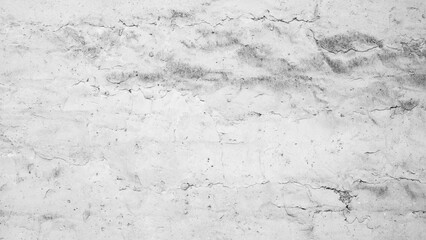 Obraz premium A white wall background with cracks and holes. The wall is made of concrete and has a rough texture