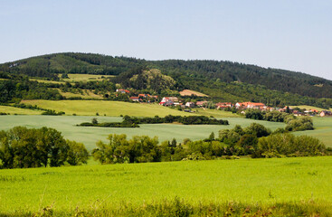 Beautiful landscape of high hills, mountains with green vegetation in the forest with the sky with a village of houses. Nature photography in Europe.