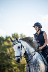 Obraz premium vertical copyspace closeup young woman rider with a helmet galloping at full speed with her horse