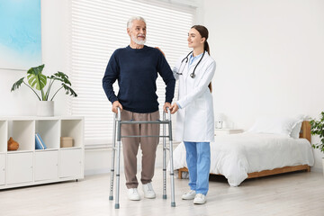 Doctor helping senior man with walking frame in clinic