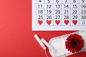 Flat lay composition with calendar and menstrual products on red background