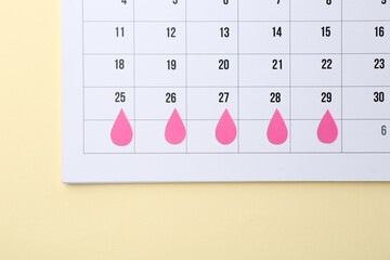 Menstruation. Calendar with marked dates on beige background, top view