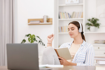 Student in headphones holding notebook and studying indoors