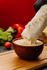 Dipping a wrap into creamy sauce, the perfect blend of flavors for food lovers