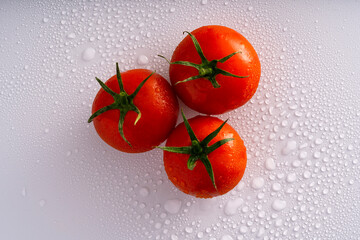fresh red wet tomatoes on wet white surface