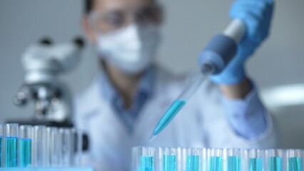 Close up of a female scientist researcher hand using a micropipette to fill up test tubes with a...