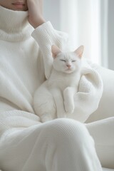 A person in a cozy, white outfit lies on a sofa with a small white cat curled up on their lap, showing a peaceful yet pained expression