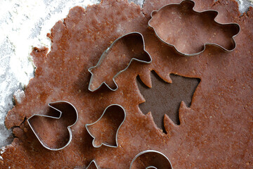 Gingerbread dough rolled out on a floured roll and various shapes of metal Christmas cookies cutters with traditional Czech motifs. The process of making traditional Christmas cookies. Flat lay