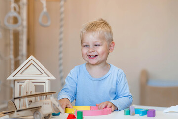 A little boy of 2 years old is playing a developing logistics constructor. Children's wooden toys....