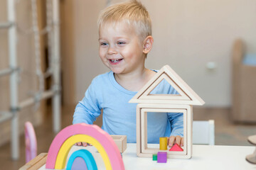 A little boy of 2 years old is playing a developing logistics constructor. Children's wooden toys....