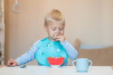 Baby food. Eating. Feeding the baby. A cute kid eats on his own with a spoon. Healthy eating. Family and children.